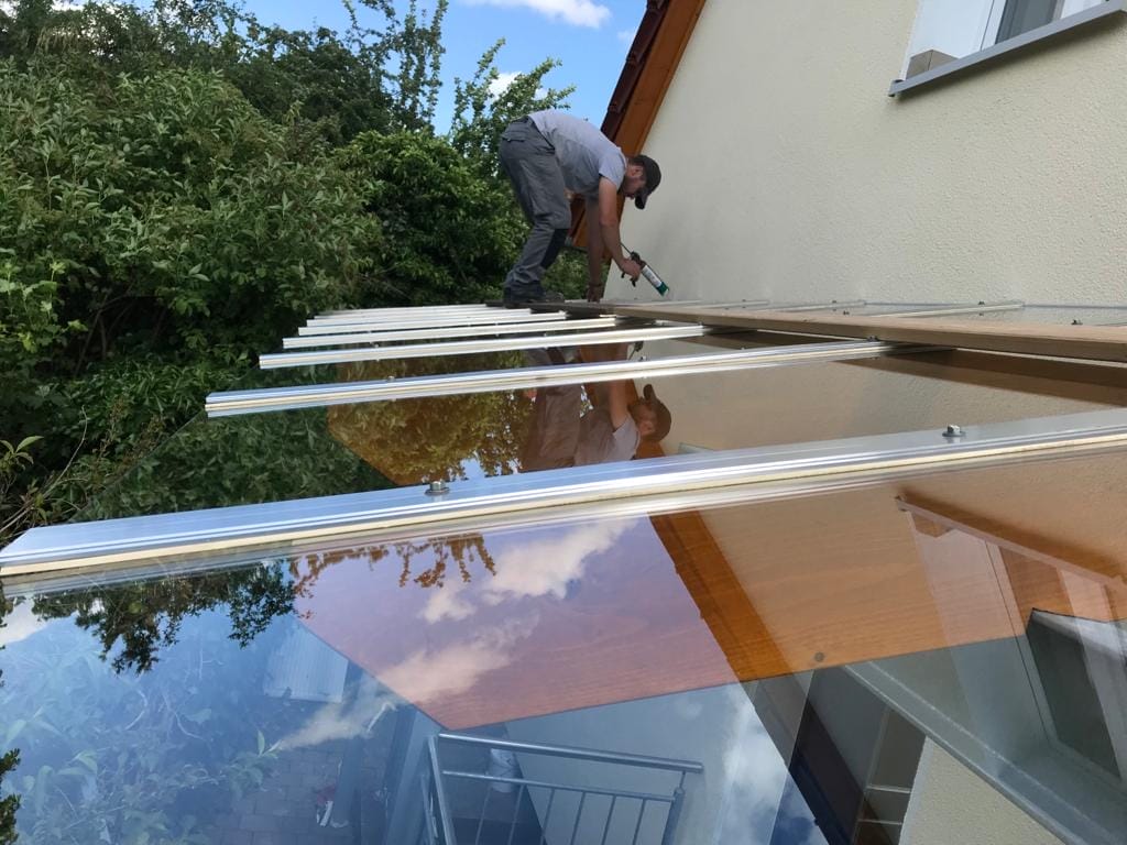 Ein Mann installiert ein Glasdach auf einem Haus.