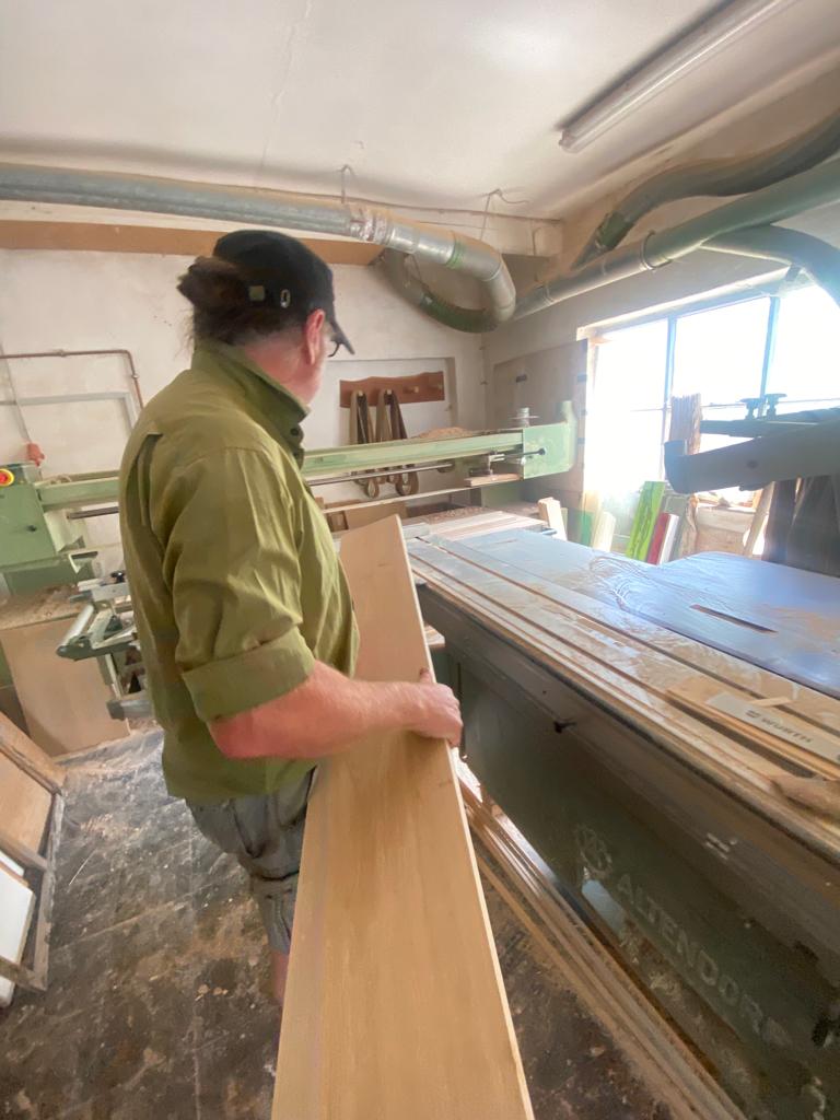 Ein Mann arbeitet an einer Maschine in einer Holzwerkstatt.