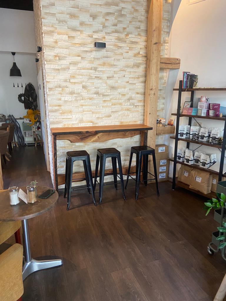Das Innere eines Cafés mit Hockern und einem Holztisch.
