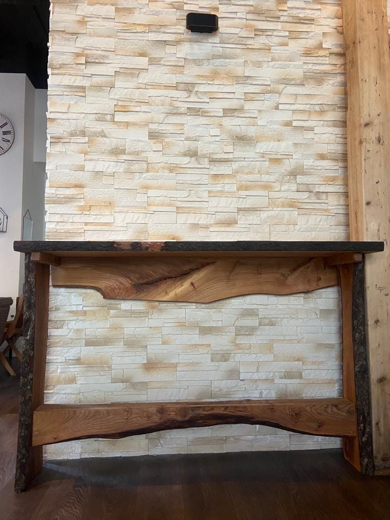 Ein Holztisch mit einer Steinmauer dahinter.