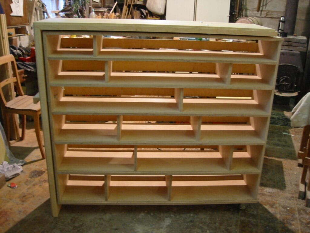 Ein Holzregal mit mehreren offenen Fächern wird in einer Werkstattumgebung bei Tischlerei Werkbau Messner Göttingen gezeigt.